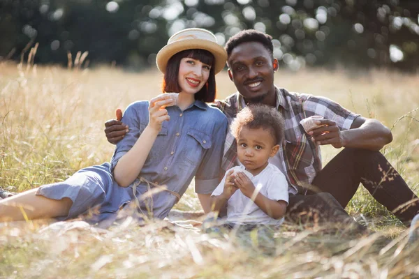 Raza mixta padres con hijo comiendo cupcakes al aire libre — Foto de Stock