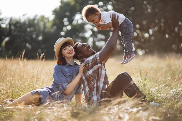 Neşeli farklı aileler sahada oğluyla oynuyorlar.