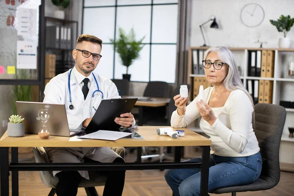 Dokter dan pasien melihat kamera saat duduk di kantor — Stok Foto