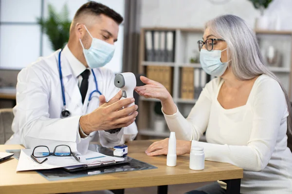 Dokter menggunakan termometer modern untuk memeriksa wanita tua — Stok Foto