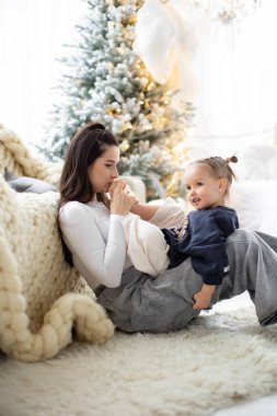 Noel sezonunda bir anne ve kızı arasında, arka planda süslü bir ağaç olan hassas bir an..