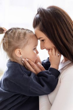 Bir anne ve küçük kızı arasında duygusal bir an, alnından alnına, sevgi ve şefkat dolu..