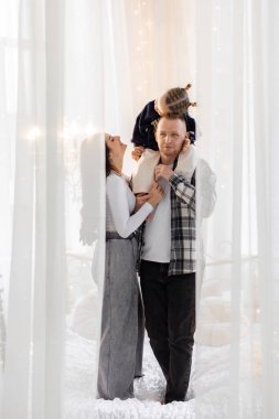 Üç kişilik mutlu bir aile, bir portre için poz veriyor, çocuğun babasının omuzlarında..