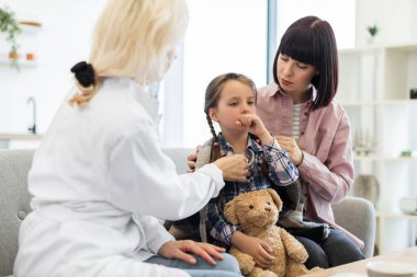 Bir doktor, genç bir kızı muayene etmek için steteskop kullanır. Annesi de onu rahatlatır. Olay yeri bir tıp bürosunda geçiyor..