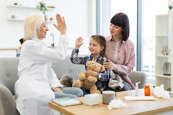 Bir doktor, muhtemelen check-up 'tan sonra annesiyle kanepede oturan genç bir kıza beşlik çakar. Kız bir oyuncak ayı tutuyor..