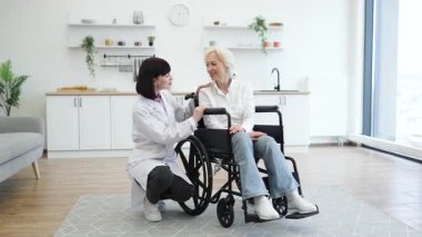 Bir doktor, son sınıf öğrencisini, parlak, modern bir mutfak ortamında tekerlekli sandalyede otururken rahatlatır..