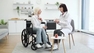 Bir doktor, tekerlekli sandalyedeki yaşlı bir hastaya danışmanlık yapar..