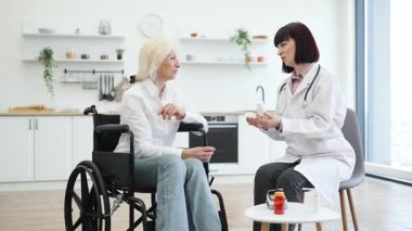 Bir doktor, tekerlekli sandalyedeki yaşlı bir hastaya ilacı açıklar. Hapları parlak ve modern bir ortamda tartışır..