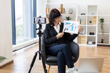 Beyaz kadın rapor ve istatistik tablosu kullanarak blog yazarak iş analitiği sunuyor..