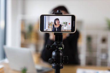 Kafkas kadın masada oturup gevşeme teknikleri, kulaklık takmak, sakinleştirme egzersizleri, modern çalışma alanı, profesyonel kurulum hakkında bir video blogu çekiyor..