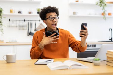 Gözlüklü genç bir adam mutfağında video görüşmesinde, şaşırmış ve elleriyle işaret ediyor..