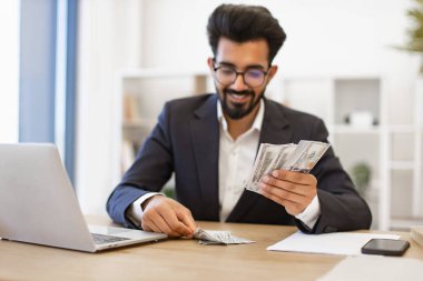 Hintli bir işadamı masasında yığınla Amerikan doları sayıyor.