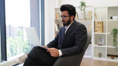 Hintli bir işadamı dizüstü bilgisayarındaki video görüşmesi sırasında gülümsüyor.