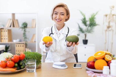 Gülümseyen bir beslenme uzmanı bir limon ve avokado tutarak sağlıklı beslenme ve diyeti teşvik eder..