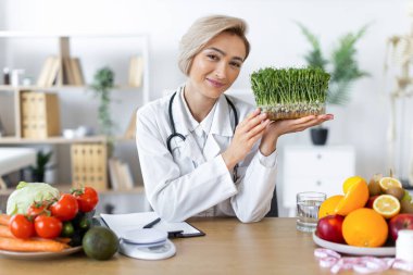 Gülümseyen bir beslenme uzmanı sağlıklı meyve ve sebzelerle çevrili bir tepsi taze lahanayı tutar ve dengeli bir diyeti teşvik eder..