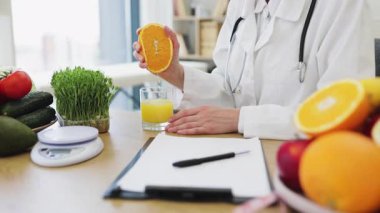 Bir beslenme uzmanı sağlıklı besin seçenekleriyle çevrili taze portakal suyu hazırlar ve dengeli bir diyet ve sağlığa teşvik eder..
