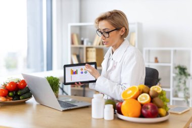 Bir beslenme uzmanı çevrimiçi konsültasyon sırasında meyve, sebze ve takviyelerle çevrili bir diyet planını açıklar..