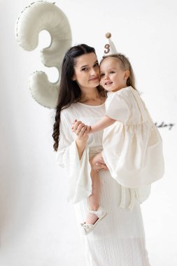 Bir anne, üçüncü doğum gününü balon ve parti şapkasıyla kutluyor..