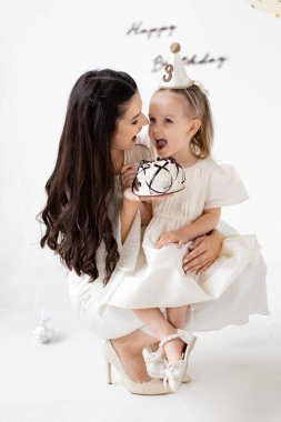 Bir anne ve kızı, doğum günü kutlaması sırasında özel bir anı bir pasta ve doğum günü arkaplanıyla paylaşır..