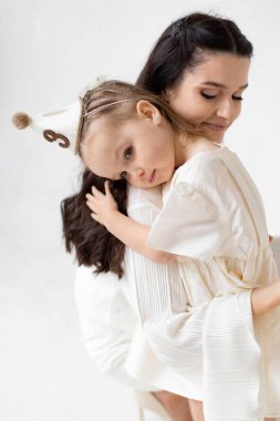 Bir anne, genç kızını şefkatle kucaklayarak sevgi ve şefkat dolu bir sahne yaratır..