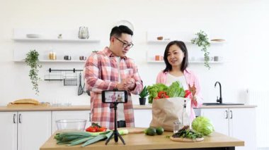 Bir aile mutfağında bir yemek videosu çekiyor. Sağlıklı bir yemek için taze sebze hazırlıyorlar.