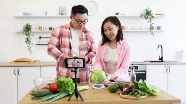 Bir çift, parlak mutfaklarında pişirme videosu için taze malzemeler hazırlıyor.