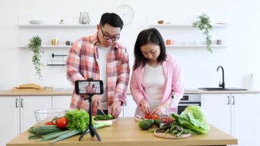 Asyalı bir çift video çekerken modern mutfaklarında yemek hazırlamaktan zevk alır.