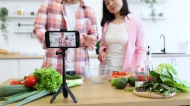 Bir çift mutfağında sağlıklı bir yemek hazırlıyor ve çevrimiçi izleyicileri için yemek pişirme dersi hazırlıyor.