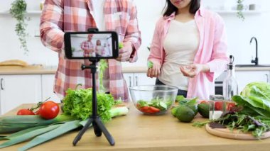 Bir çift, sosyal medya için video çekerken mutfakta salata hazırlıyor.