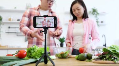 Neşeli bir çift mutfağında taze sebzeleri eğlence için kullandıkları bir yemek videosu çekiyor.