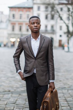 Takım elbiseli genç bir zenci, elinde deri bir çantayla Avrupa 'nın bir caddesinde güvenle yürüyor.