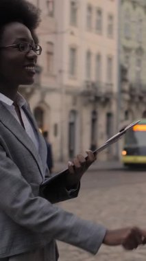 Resmi giyinmiş genç bir Afrikalı erkek ve kadın şehir caddesinde birlikte durup panoya bakıyorlar. İki meslektaş dışarıda iş projesini tartışıyor..