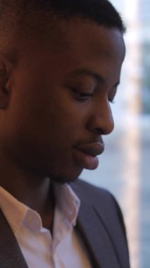 Close up portrait of young african businessman in stylish suit resting during a break. Confident man sitting at cafe table and working on distance.