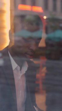 Yakışıklı afro amerikalı takım elbiseli adam rahat bir kafede otururken evrak ve tabletle çalışıyor. İnsan kavramı, teknoloji ve iş dünyası.