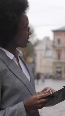 İş elbiseleri giymiş Afrikalı erkek ve kadın ortaklar sokakta dikilip konuşuyorlar. İki meslektaş temiz hava hakkında konuşuyor..