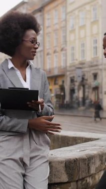 Güzel bir Afrikalı kadın ve yakışıklı bir adam şehir caddesinde buluşuyor. Dışarıda çalışma saatlerini tartışan resmi kıyafetli iki iş ortağı..