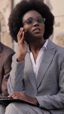 Yakışıklı takım elbiseli adam dijital tablet üzerinde çalışırken çekici kadın cep telefonuyla konuşuyor ve panoya yazı yazıyor. Ofis dışındaki sorunları çözen iki Afrikalı meslektaşım..