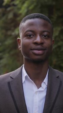 Close up portrait of confident businessman in stylish suit standing on street. Handsome african man smiling and relaxing during a break outdoors.