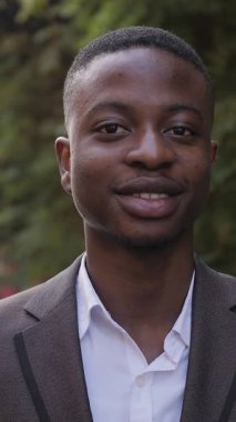 Close up portrait of confident businessman in stylish suit standing on street. Handsome african man smiling and relaxing during a break outdoors.