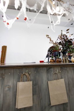 Cadılar Bayramı için duvarda örümcek ağları, balkabakları ve kağıt torbalarla bir dükkan süslenir.