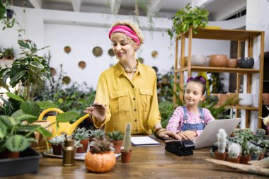 Bir kadın ve genç bir kız çeşitli bitki ve sularla çevrili bir fabrikada birlikte çalışıyorlar.