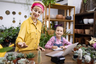 Bir kadın ve genç bir kız yeşillik ve sularla çevrili bir fabrikada birlikte çalışıyorlar.