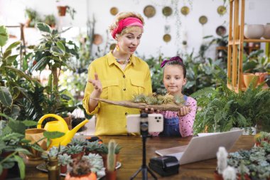 Bir kadın ve bir kız fabrikadaki hava tesisleri hakkında bir video çekiyorlar.