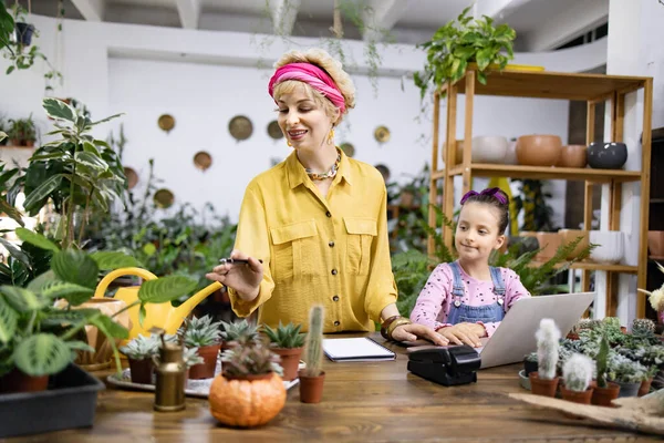 Bir kadın ve genç bir kız çeşitli bitki ve sularla çevrili bir fabrikada birlikte çalışıyorlar.