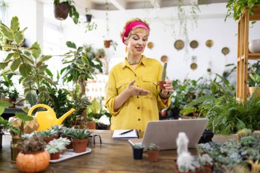 Bir kadın bir fabrikada online sunum yaparken kaktüs tutuyor.