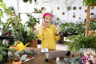 Sarı gömlekli bir kadın, fabrikada telefonla konuşurken iyi hareket eder.