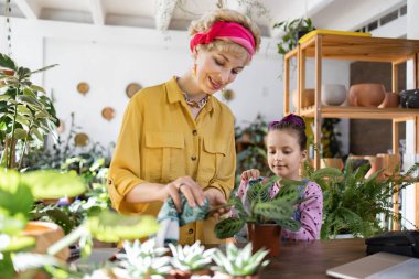 Bir anne ve kızı, parlak ve davetkar bir alanda birlikte bitki yetiştirmekten hoşlanırlar.