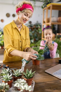 Bir kadın ve genç bir kız, parlak ve davetkar bir mekanda birlikte bitki yetiştirmekten mutluluk duyarlar.