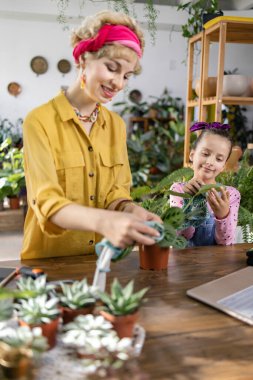 Bir anne ve kız birlikte bitki yetiştirmekten zevk alır, aile ve doğa için iç açıcı bir sahne yaratır.