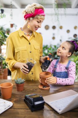 Bir kadın ve genç bir kız, küçük sulu bir bitki ekme görevine odaklanırlar.